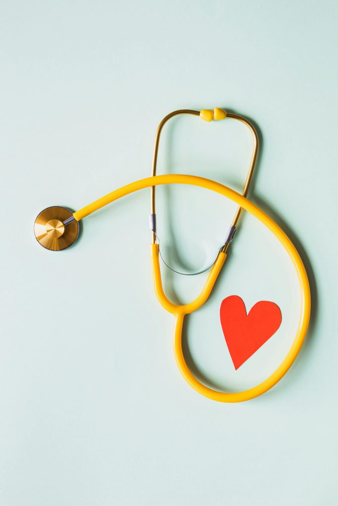 pexels-photo-4386467-4386467 Yellow stethoscope arranged with a red heart cutout on a light green background, symbolizing heart health.